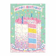 Kolorowa kartka urodzinowa z puzzlami przedstawiająca tort na tle konfetti z napisem Happy Birthday